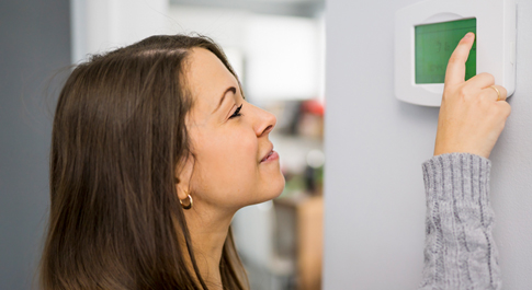 Woman adjusting thermostat